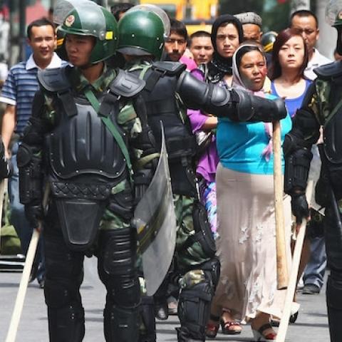 Uighur people (C) walk near police as they form a line across a street on July 8, 2009 in Urumqi, China. (Guang Niu/Getty Images)