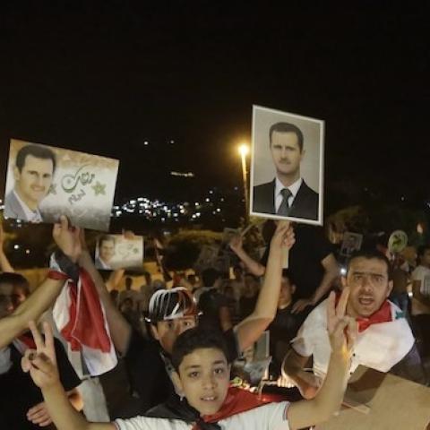 Syrians hold pictures of re-elected Syrian President Bashar al-Assad in Damascus after Assad was announced as the winner of the country's presidential elections on June 4, 2014. (JOSEPH EID/AFP/Getty Images)