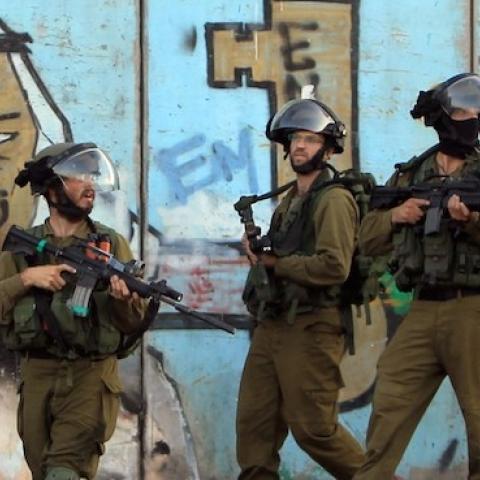 Israeli soldiers in front of the separation-barrier during clashes with Palestinian stone throwers, at the Israeli Qalandiya checkpoint, August 13, 2014. (ABBAS MOMANI/AFP/Getty Images)