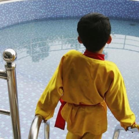 A young boy views a private swimming pool at a luxury residential area in Jiangmen, Guangdong Province, China, Febuary 15, 2005. (Cancan Chu/GettyImages)