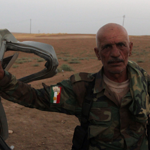 A Peshmerga fighter next to the remains of a car bearing the Islamic State's trademark jihadist flag after an American air strike in the village of Baqufa, north of Mosul, on August 18, 2014. (AHMAD AL-RUBAYE/AFP/Getty Images)