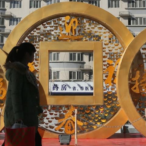 People walk past a copper coin-shapped decoration for Chinese New Year on January 20, 2014 in Zhengzhou, China. (ChinaFotoPress/ChinaFotoPress via Getty Images)
