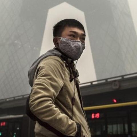 A Chinese man wears a mask as he waits to cross the road near the CCTV building during heavy smog on November 29, 2014 in Beijing, China. (Kevin Frayer/Getty Images)
