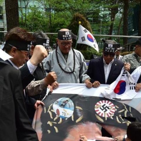 South Korean activists tear a banner showing a picture of Japan's Prime Minister Shinzo Abe during a protest outside the Japanese embassy in Seoul on April 28, 2015. (JUNG YEON-JE/AFP/Getty Images)
