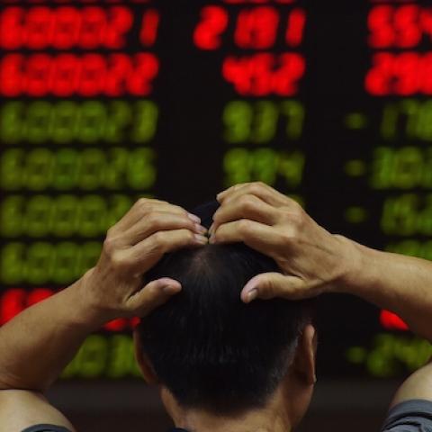 An investor looks at screens showing stock market movements at a securities company in Beijing on July 14, 2015. (GREG BAKER/AFP/Getty Images)