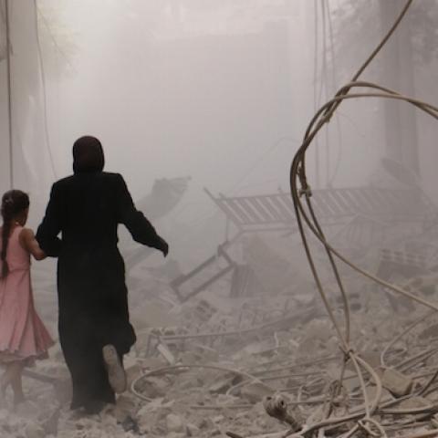 A woman and child run through the smoke after an air-strike staged by Syrian regime forces in Duma district, Damascus, Syria on September 28, 2015. (Mohammed Khair/Anadolu Agency/Getty Images)