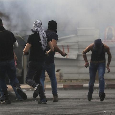 Palestinian protesters hurl rocks at an Israeli armoured vehicle (background) during clashes next to the Jewish settlement of Beit El, north of Ramallah on October 19, 2015. (ABBAS MOMANI/AFP/Getty Images)