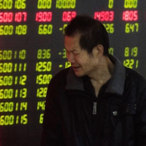 An investor looks at screens showing stock market movements at a securities company in Beijing on January 5, 2016. (FRED DUFOUR/AFP/Getty Images)