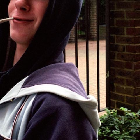 Stoned teenage boy smoking spliff and triumphantly holding a bag of weed, Lambeth Walk South London c.2000. (PYMCA/UIG via Getty Images)