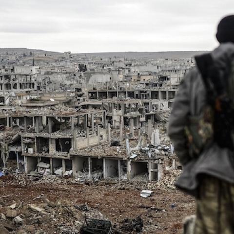 Musa, a 25-year-old Kurdish marksman, stands atop a building as he looks at the destroyed Syrian town of Kobane on January 30, 2015. (BULENT KILIC/AFP/Getty Images)