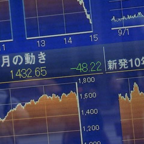 A man walks past a screen showing global stock market information on the street in Tokyo on August 25, 2015. (Chris McGrath/Getty Images)
