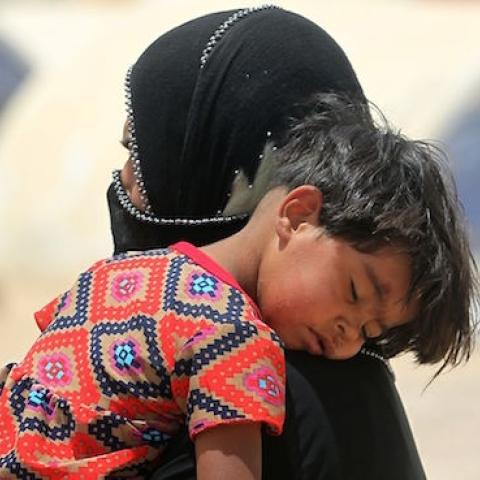 An Iraqi woman displaced from the city of Fallujah carries a child at a newly opened camp where hundreds of displaced Iraqis are taking shelter in Amriyat al-Fallujah on June 27, 2016, south of Fallujah. (AHMAD AL-RUBAYE/AFP/Getty Images)