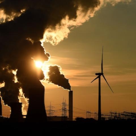 Electricity pylons and wind turbines stand beside a coal-fired power plant while steam rises from cooling towers near Bergheim, Germany (Photo by Volker Hartmann/Getty Images)