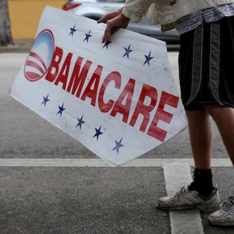 A man holds up a sign directing people to an insurance company where they can sign up for the Affordable Care Act (Photo by Joe Raedle/Getty Images)