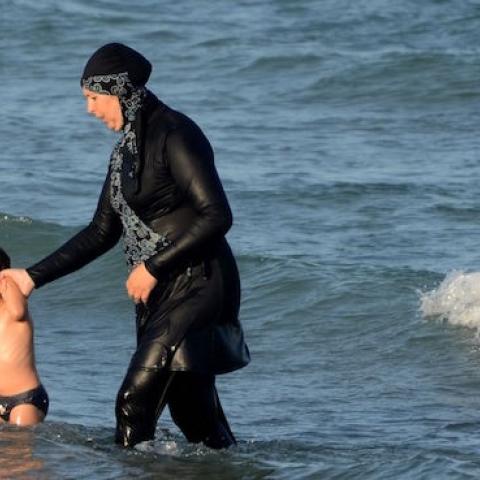 A Tunisian woman wearing a 'burkini' walks in the water with a child on August 16, 2016 at Ghar El Melh beach near Bizerte, north-east of the capital Tunis. (FETHI BELAID/AFP/Getty Images)