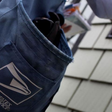 US Postal Service letter carrier places letters in a mailbox as he walks his delivery route July 30, 2009 in San Francisco, California. (Justin Sullivan/Getty Images)