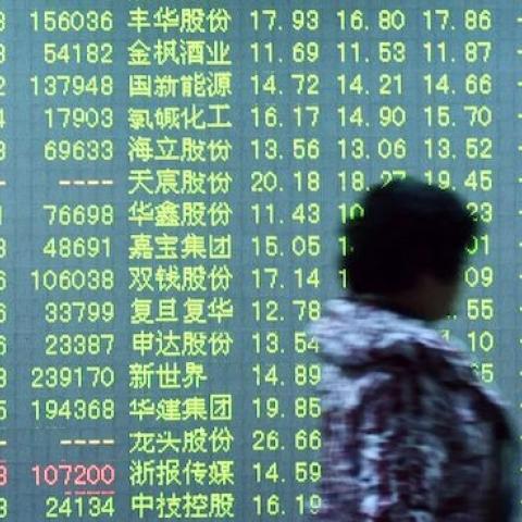 An investor walks past a screen showing stock market movements at a securities firm in Hangzhou, in eastern China's Zhejiang province on January 11, 2016. (STR/AFP/Getty Images)