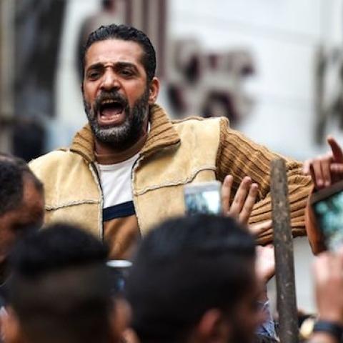 An Egyptian raises a cross made of palm leaves, originally intended for Palm Sunday celebrations, as he is being lifted by others at the Coptic Orthodox Patriarchate in Alexandria, April 9, 2017. (MOHAMED EL-SHAHED/AFP/Getty Images)