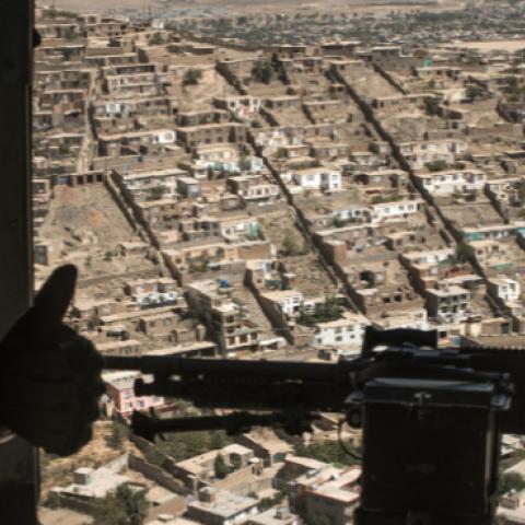 A U.S. Army advisor for the Afghan Air Force signals the Afghan crew chief during a training mission outside of Kabul, September 13, 2017 (Andrew Renneisen/Getty Images)