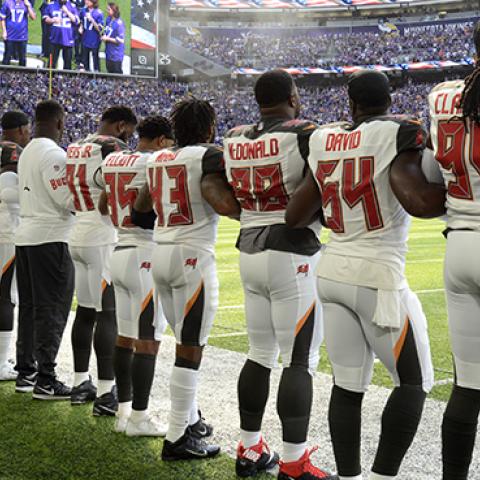 Tampa Bay Buccaneers players link arms on the sidelines during the national anthem before the game against the Minnesota Vikings, September 24, 2017 (Hannah Foslien/Getty Images)