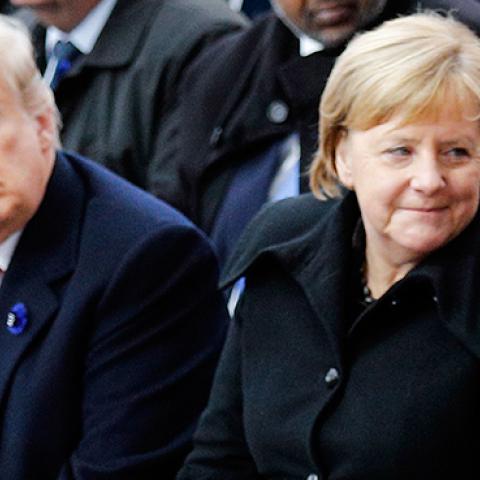 French President Emmanuel Macron Speaks to German Chancellor Angela Merkel as they sit next to US President Donald Trump and US First Lady Melania Trump in Paris on November 11, 2018 (Photo credit: FRANCOIS MORI/AFP/Getty Images)