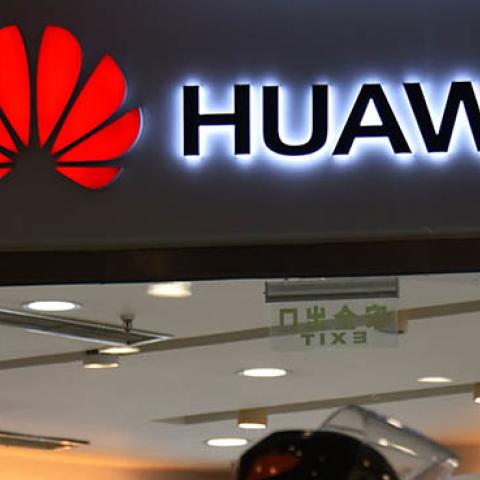 This photo taken on December 10, 2018 shows people walking past a Huawei store in Beijing. (Photo credit: GREG BAKER/AFP/Getty Images)