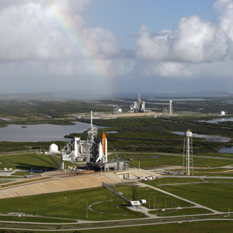 With a rainbow serving as a backdrop in the sky, space shuttle Atlantis (foreground) sits on Launch Pad A and Endeavour on Launch Pad B at NASA's Kennedy Space Center in Florida. (Stocktrek Images)