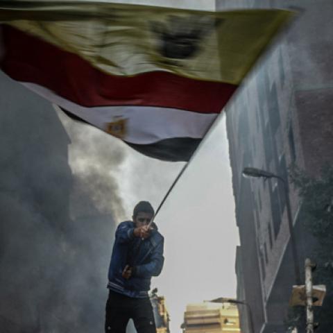 An Egyptian protester raises flags during the clashes between Egyptian police and protesters after declaring the Muslim Brotherhood as a terrorist group in Alf Maskan district of Cairo, Egypt, December 27, 2013. (Getty Images)