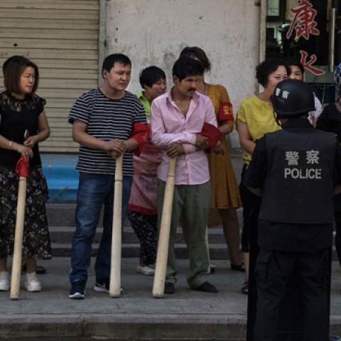 A mix of ethnic Uyghur and Han shopkeepers hold large wooden sticks as they are trained in security measures on June 27, 2017 next to the old town of Kashgar, in the far western Xinjiang province, China. (Kevin Frayer/Getty Images)