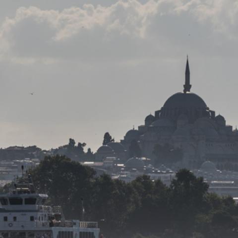 A ferry navigates the Bosphorus Strait in front of a Turkish flag and the Suleymaniye Mosque in Istanbul, Turkey. (Getty Images)