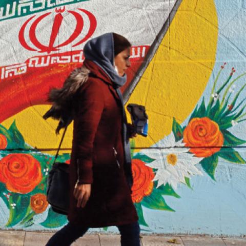 An Iranian woman walks past a mural painting of the Islamic republic's national flag in central Tehran on November 21, 2019.