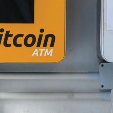 A woman uses her phone as she walks past an ATM for the digital currency bitcoin in Hong Kong on Dec. 18, 2017
