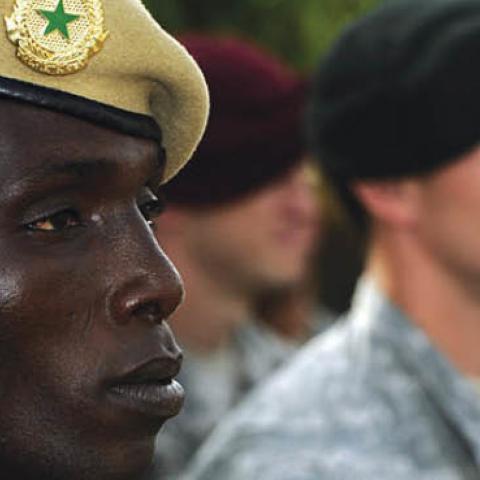 A Malian solider stands with U.S. military personnel.
