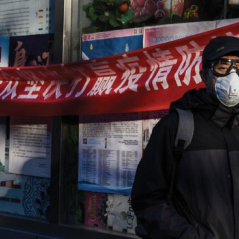 A Chinese man wears a protective mask as he walks by a health banner related to the coronavirus outbreak at a local market on March 4, 2020 in Beijing, China. (Kevin Frayer/Getty Images)