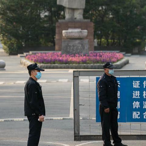  Security men wearing protective masks stand near a statue of former Chinese leader Mao Zedong at a gated entrance of Tongji University on March 17, 2020 in Shanghai, China.