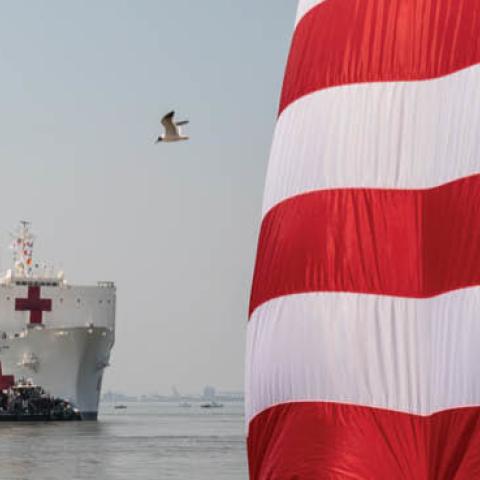 America flags are presented for the send of the U.S. Navy hospital ship USNS Comfort at Naval Air Station Norfolk Pier 8, Saturday, March 28, 2020, as she gets underway for New York City where she will support the city’s response to COVID-19. 