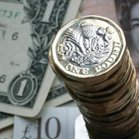 A stack of £1 coins is seen with the new £10 note alongside US dollar bills on October 13, 2017 in Bath, England