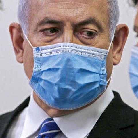 Israeli Prime Minister Benjamin Netanyahu (C), wearing a protective face maks, speaks with his lawyer inside a courtroom at the district court of Jerusalem on May 24, 2020, during the first day of his corruption trial.
