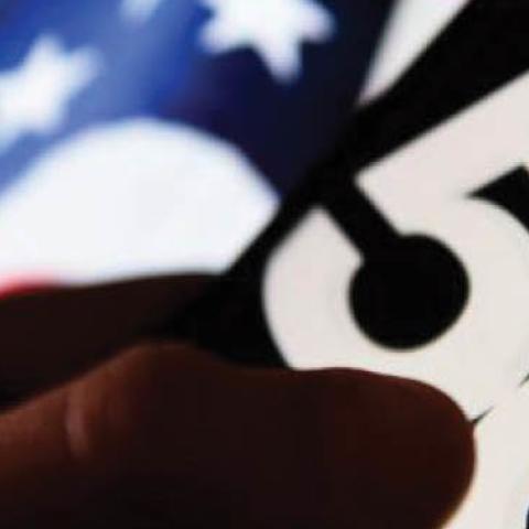 The 5G logo is seen displayed on an Android mobile phone with United States of America flag in the background
