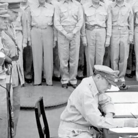 English: General Douglas MacArthur signs as Supreme Allied Commander during formal surrender ceremonies on the USS MISSOURI in Tokyo Bay.
