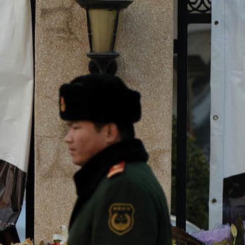 A Chinese policeman walks past a memorial to the late South African leader Nelson Mandela outside the South African embassy in Beijing on December 11, 2013. 