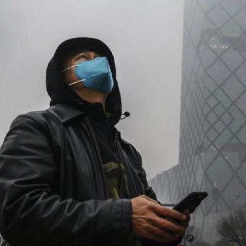 The CCTV building, shrouded in fog and pollution, during rush hour in Beijing.