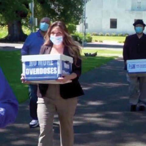 Volunteers carry boxes of signed petitions for a ballot measure decriminalizing a number of hard drugs in Salem, Ore., June 26.