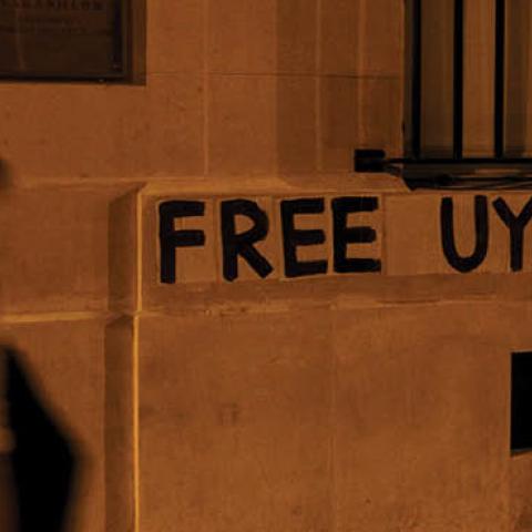 A woman walks past a banner pasted by members of a collective against violence towards women in support of the Uighur population on a wall of China's Embassy in Paris on July 30, 2020.