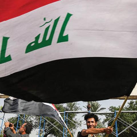 A demonstrator waves a large Iraqi national flag during an anti-government protest. (Photo by AHMAD AL-RUBAYE/AFP via Getty Images)