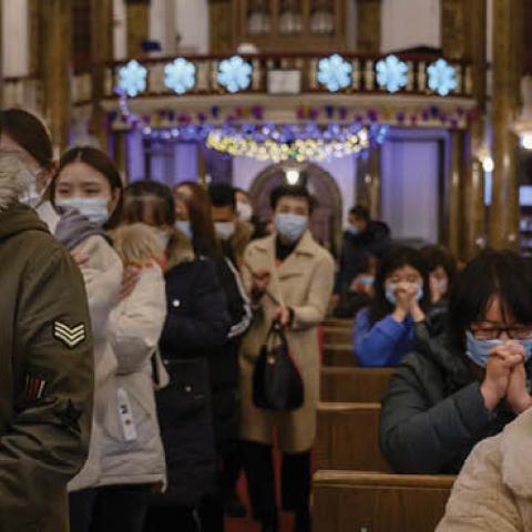 Chinese Christians pray and wait in line to take communion during a Christmas Mass at a Catholic Church on December 24, 2020 in Beijing, China