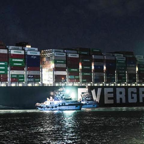 This picture taken late on March 27, 2021 shows a view of tugboats by the Panama-flagged MV 'Ever Given' (operated by Taiwan-based Evergreen Marine) container ship, which has been wedged diagonally across the span of the canal about six kilometres north o