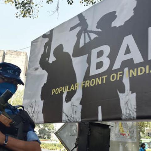 Rapid Action Force (RAF) personnel stand guard beside a banner installed by the supporters and activists of India's ruling Bharatiya Janata Party (BJP) during a protest demanding ban on Popular Front of India (Getty Images)
