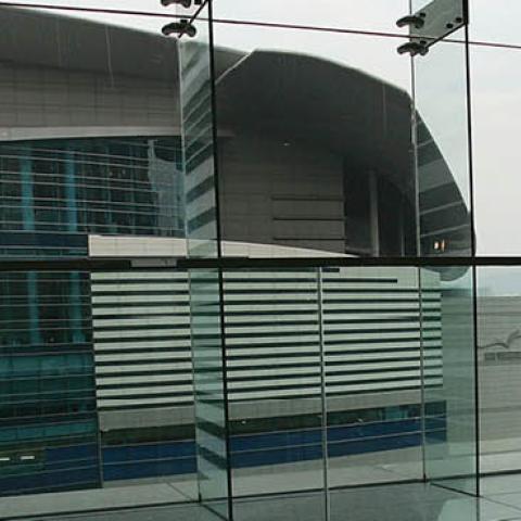 A delegate stands in front of a window at the Hong Kong Convention and Exhibition Centre during the World Trade Organization (WTO) ministerial conference on 16 December, 2005 in Hong Kong (Photo by MN Chan/Getty Images)