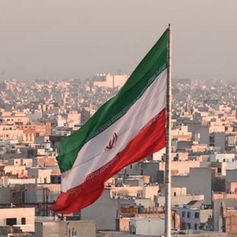 Iranian flag waving with city skyline on background in Tehran, Iran (Getty Images)